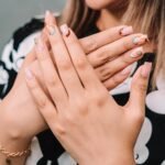 Close-up of a woman's hands with artistic nail designs and a bracelet, showcasing elegance.